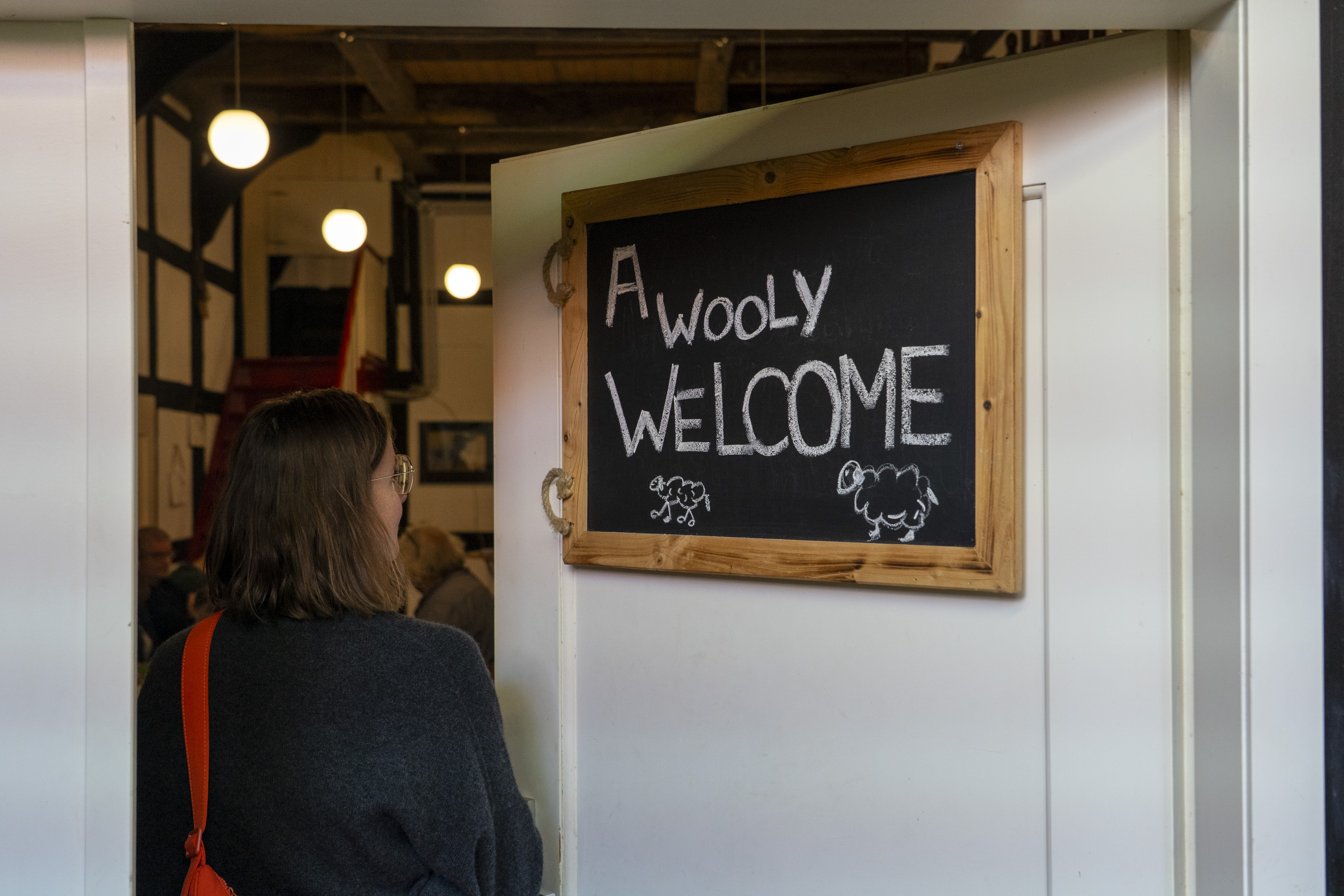 Eine Frau neben dem Schild "A wooly welcome"