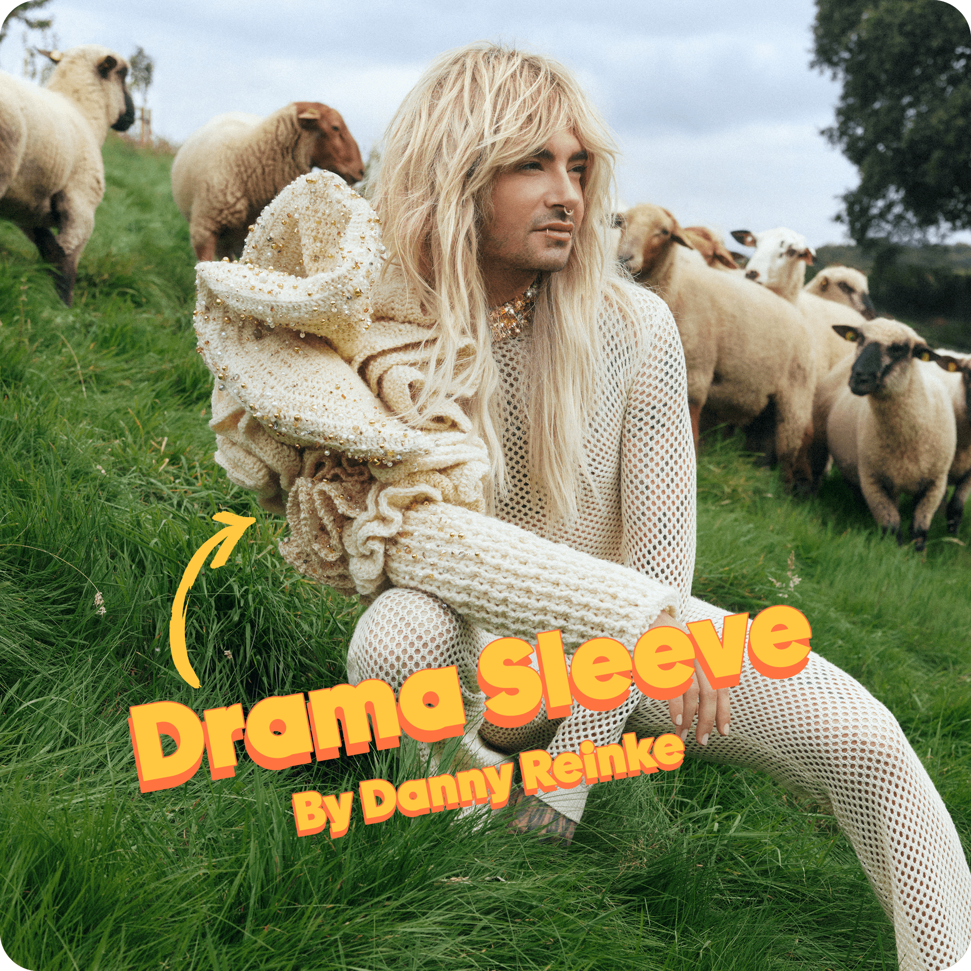 Bill Kaulitz posierend  auf der Rainbowwool Farm mit dem Drama-Sleeve, während im Hintergrund Schafe grasen.